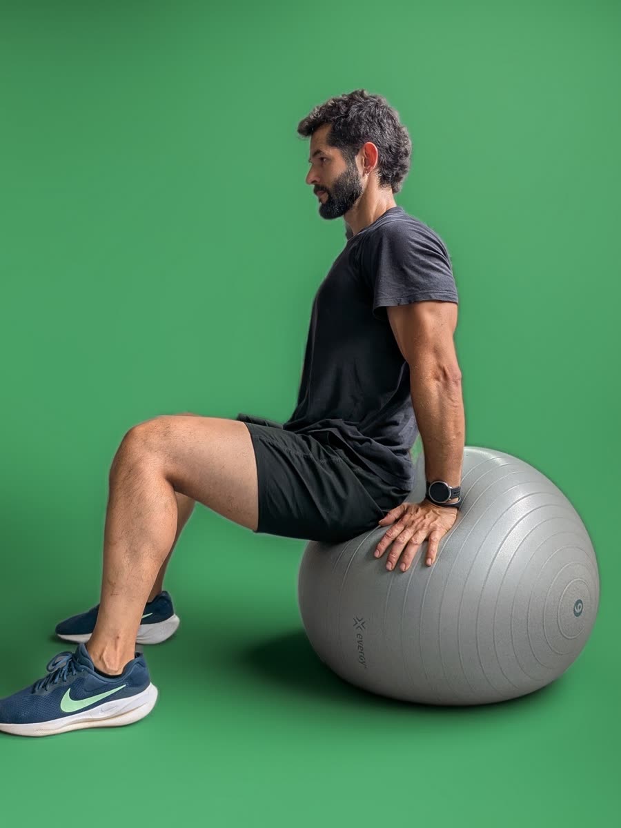 Alberto sentado de perfil sobre un fitball, con la espalda erguida
